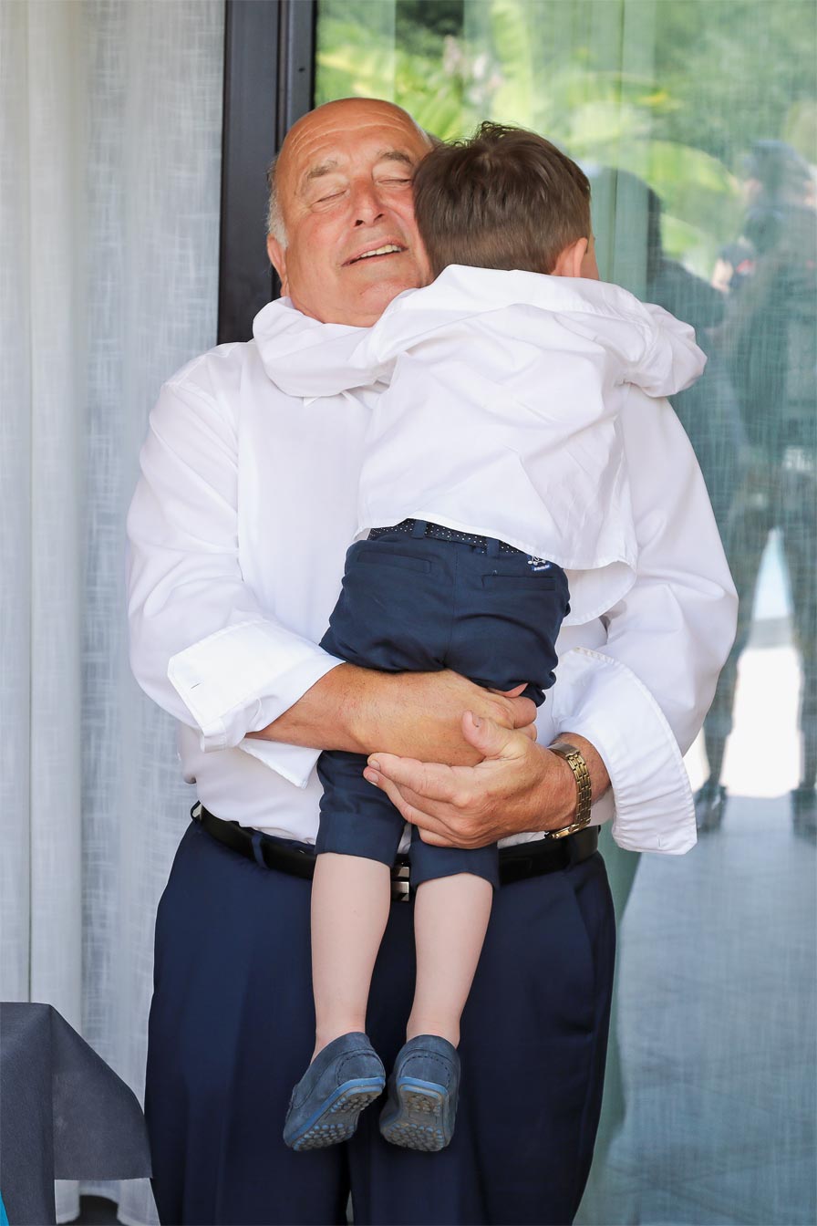 grand-père et son petit fils se serrent dans les bras pour le jour de son baptême